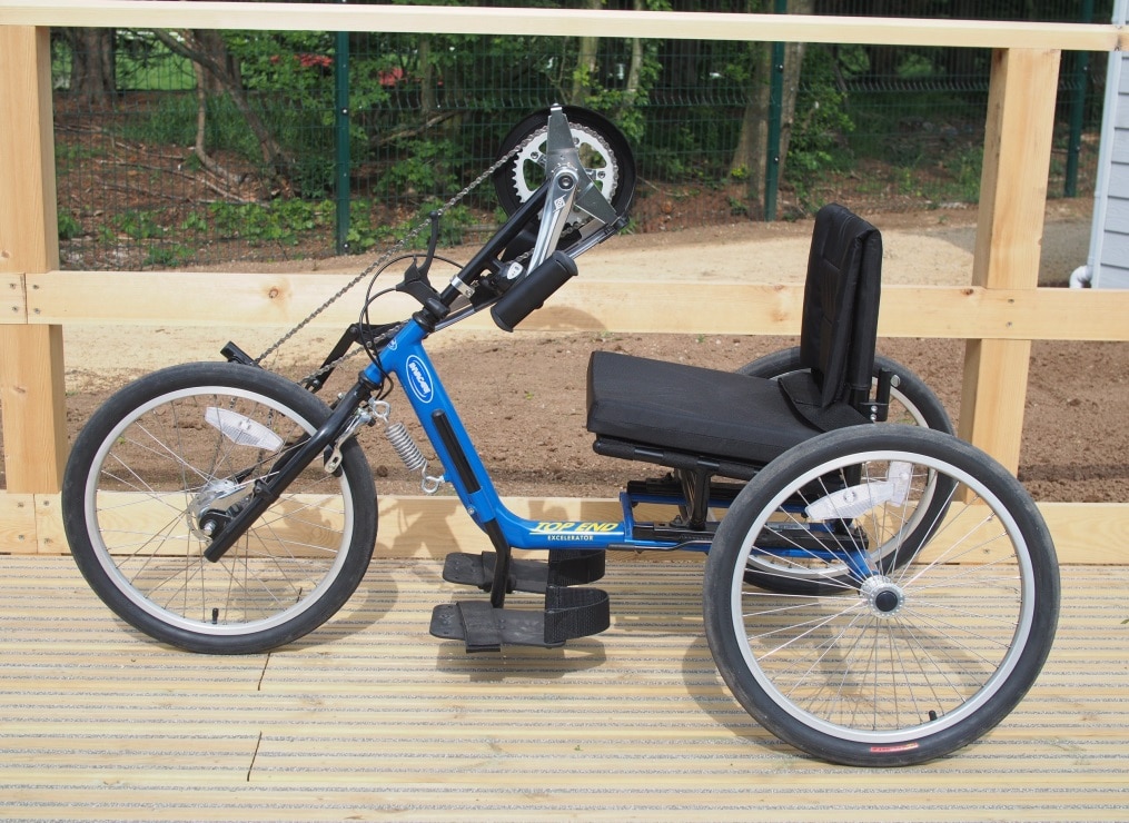 A blue adult size handcycle on a wooden platform