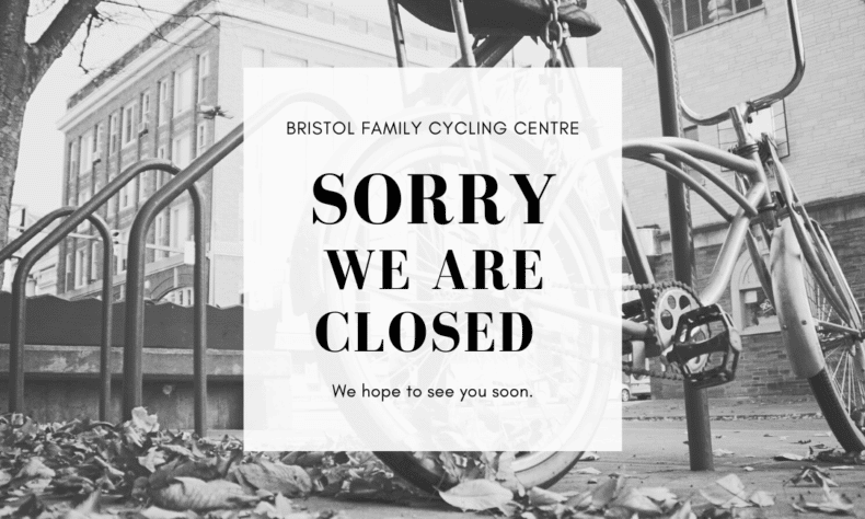 Black and white photo of a parked bike with sorry we are closed sign