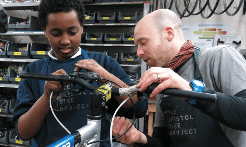 Photo of boy being shown how to fix a bike